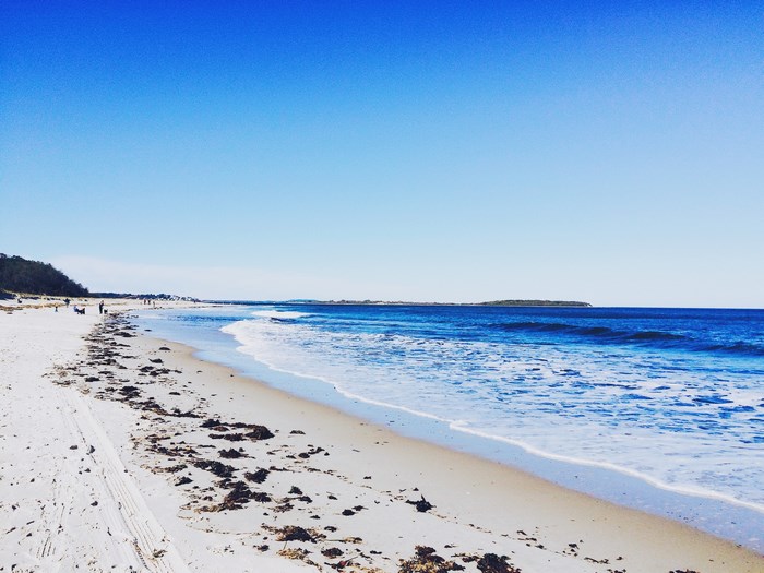 Sandy beach with ocean waves and distant island