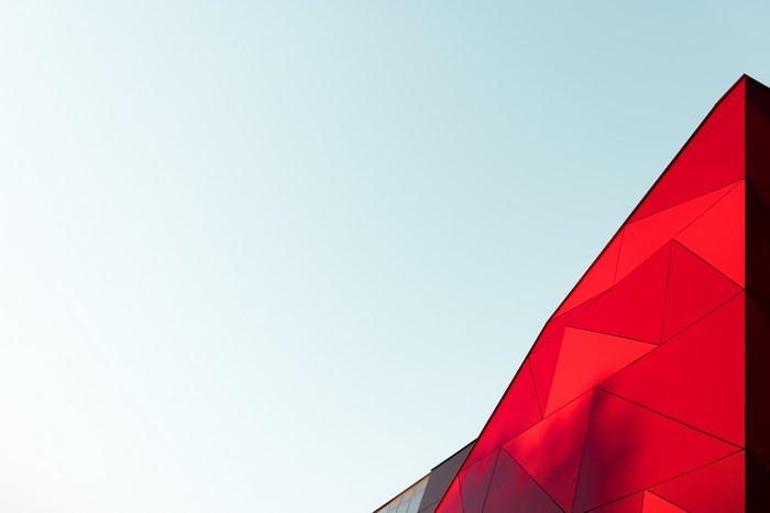 Red geometric building facade against a clear sky