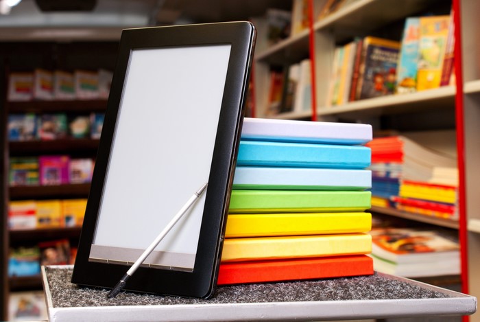 Tablet with stylus and colorful books in a library