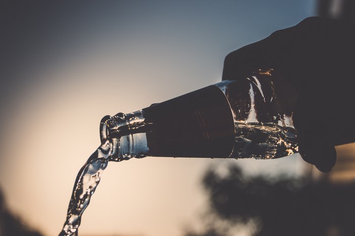 Water pouring from a bottle at sunset