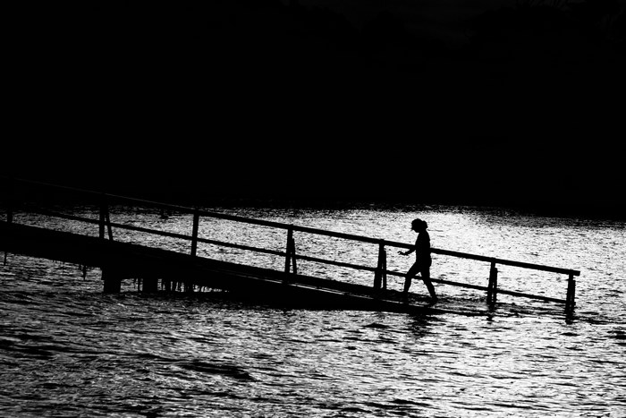 Silhouette of a girl walking on a pier over water