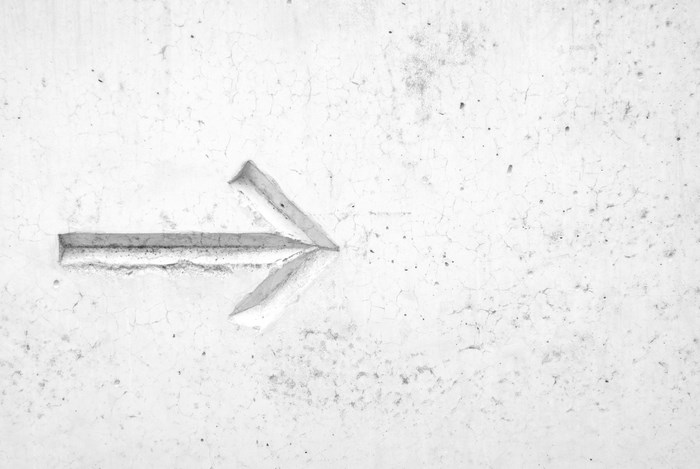 Carved arrow on a textured concrete wall