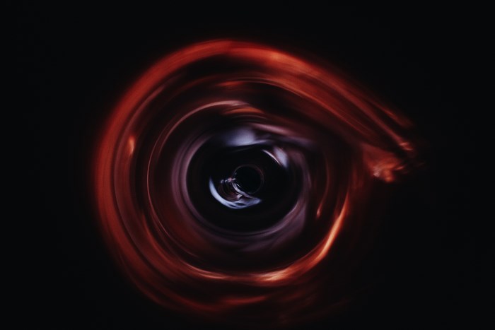 Abstract swirling red and purple light resembling a wormhole or black hole