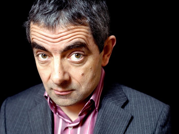Rowan Atkinson wearing a suit and striped shirt