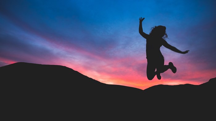 Silhouette of a woman jumping against a sunset sky