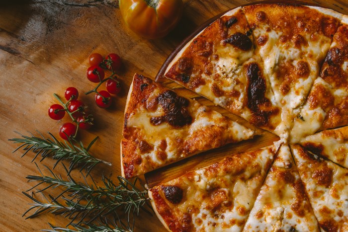 Pizza with cherry tomatoes and rosemary on a wooden board