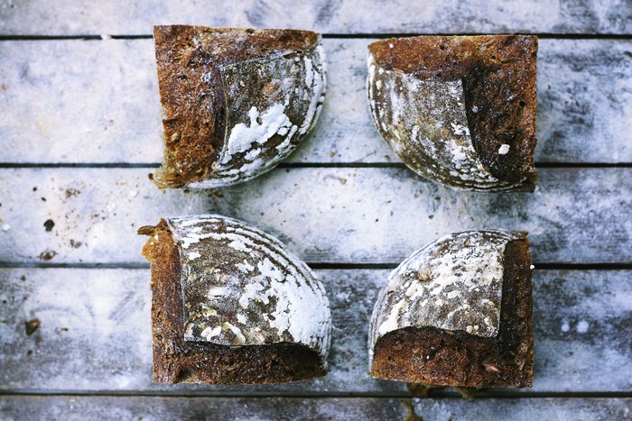 Four pieces of rye bread dusted with flour on a wooden table