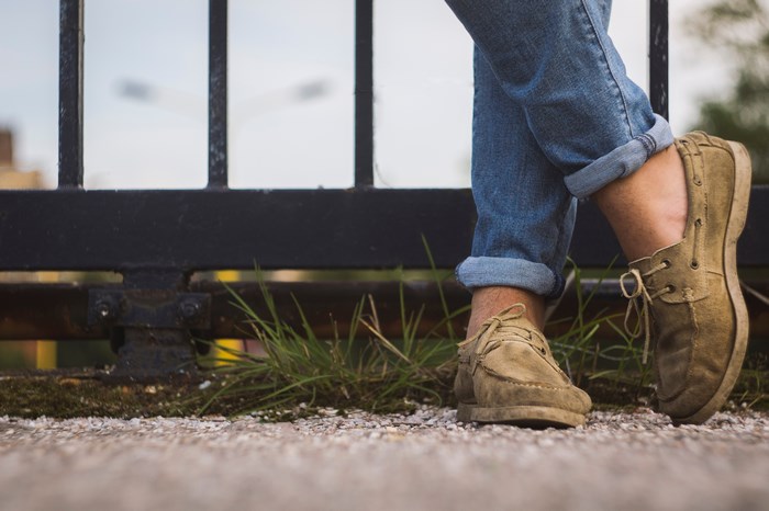 Person in jeans and loafers by a gate