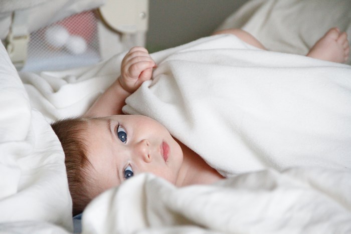 Baby boy lying in a crib under a blanket