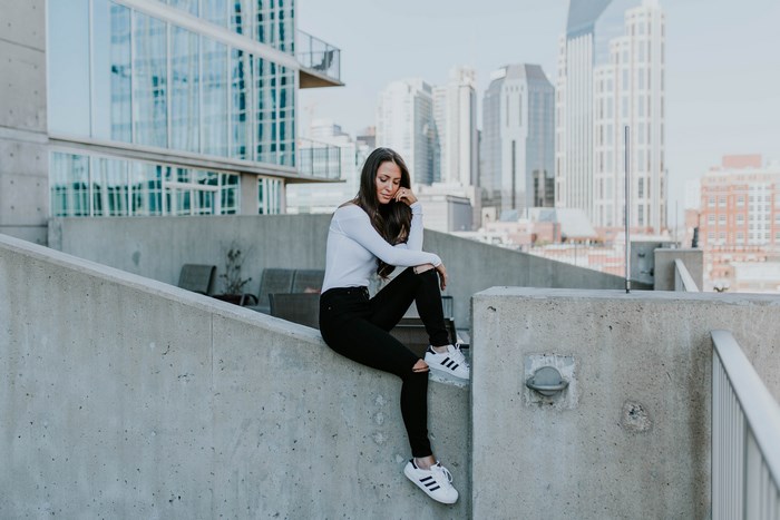 Woman in ripped jeans sitting on a concrete ledge