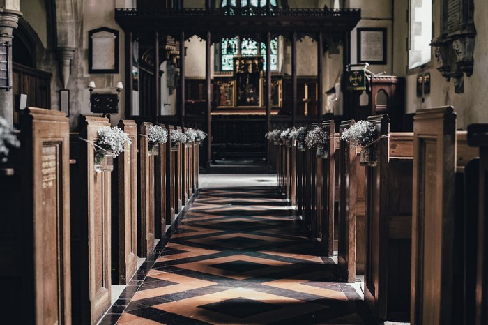 Church aisle with wooden pews and floral decorations