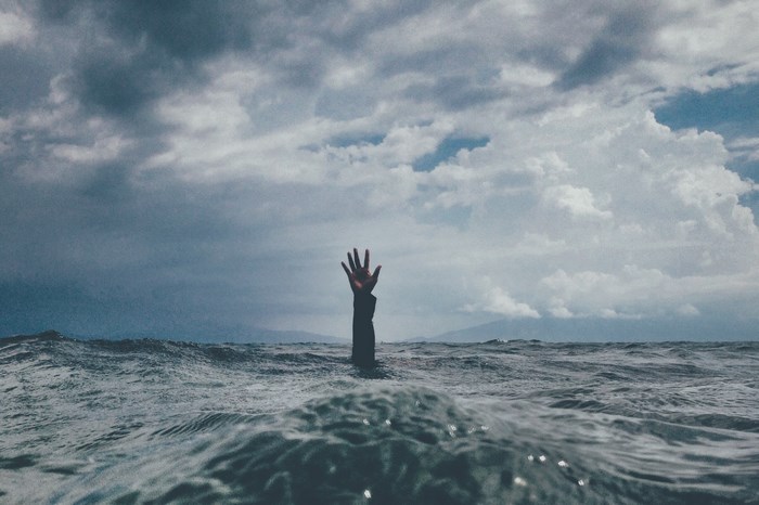 Hand reaching out of stormy ocean water