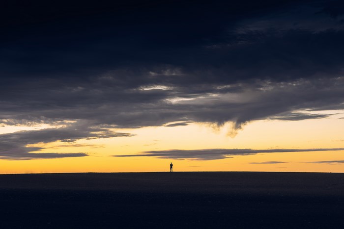 Silhouette of a person on a barren horizon at sunset