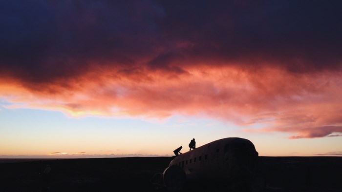 Silhouettes on a crashed plane at sunset in Iceland