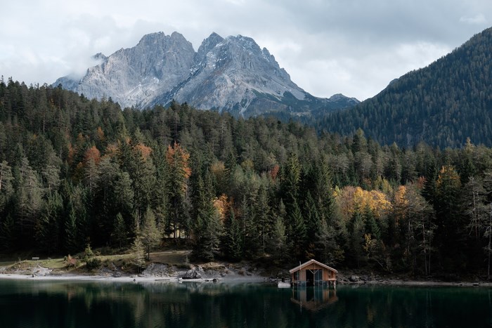 Wooden cabin on a lake with mountains and forest