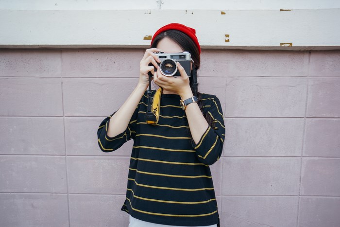 Woman in red hat taking a photo with a camera