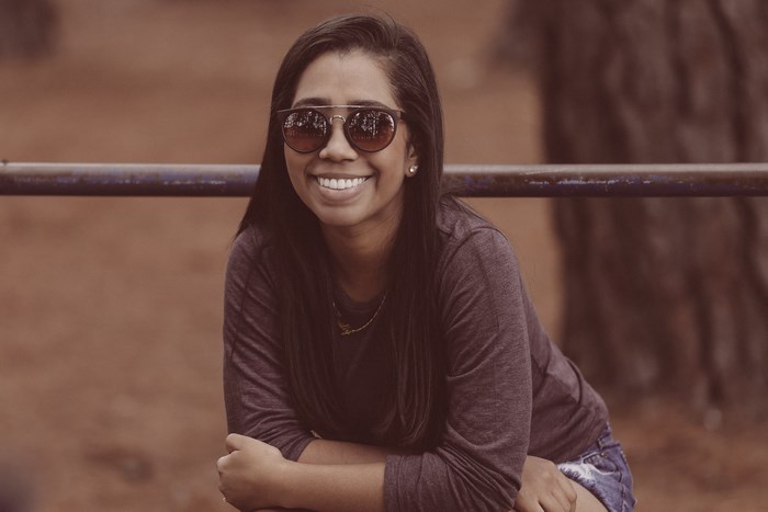 Woman wearing sunglasses and a grey shirt smiles