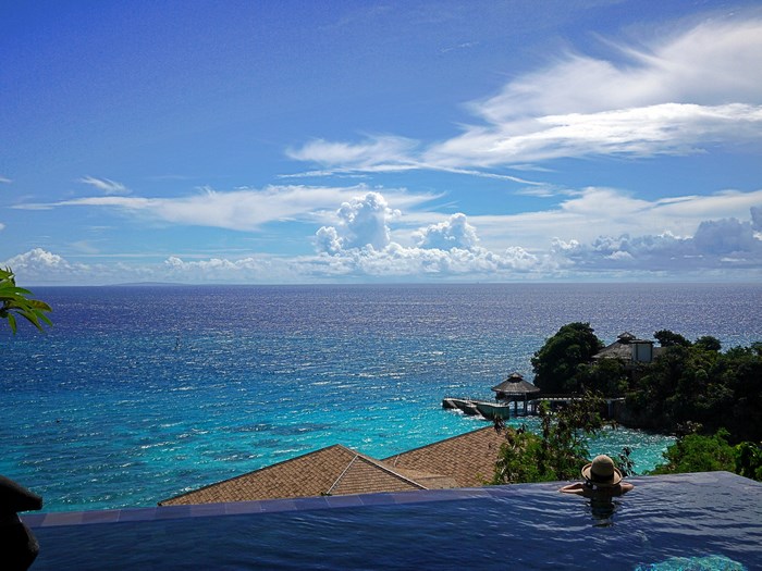 Woman in pool overlooking tropical ocean view
