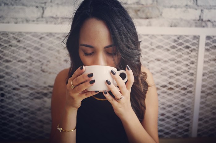 Woman drinking from a white cup