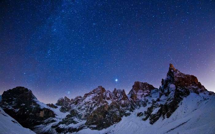Snowy mountains under a starry night sky