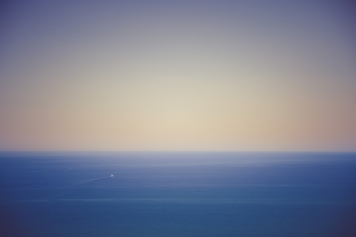 Ocean horizon with a boat and gradient sky