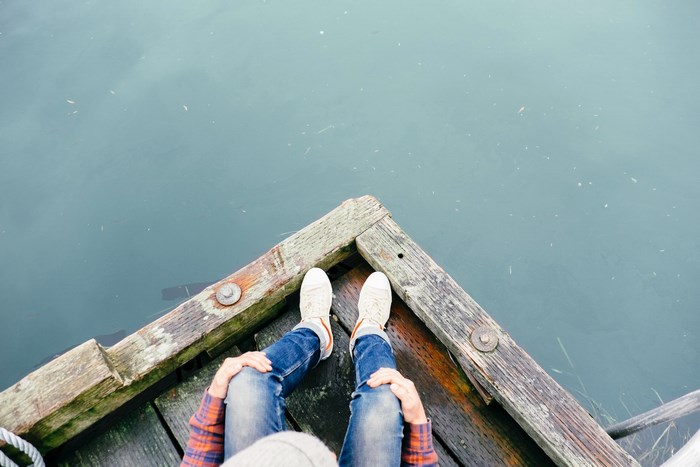 Person sitting on a wooden dock by the water