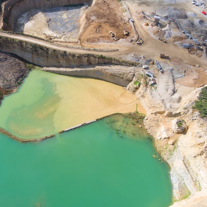 Aerial view of a quarry with turquoise water and machinery