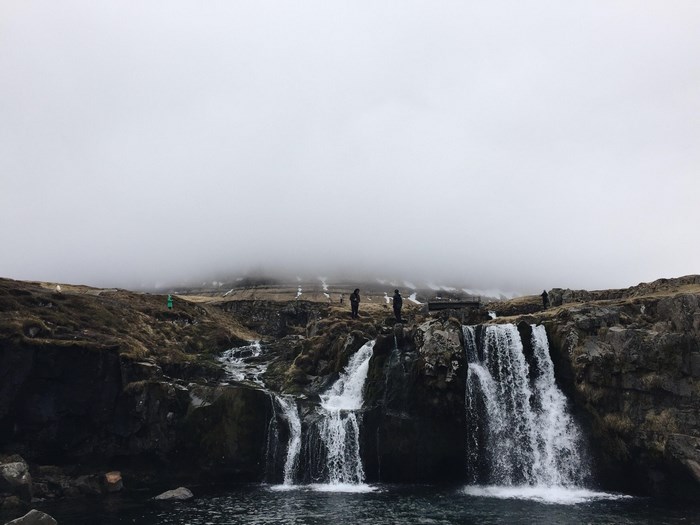 People standing by a foggy waterfall in Iceland