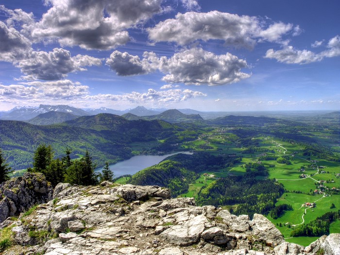 View from a rocky mountain peak over a lake and green landscape
