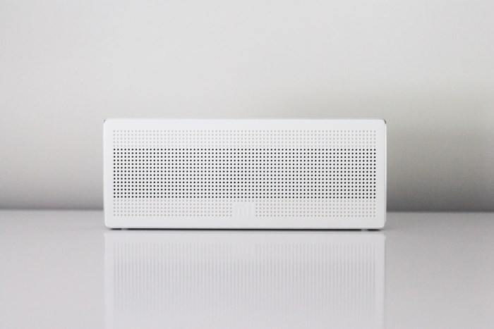 White perforated speaker on a reflective surface