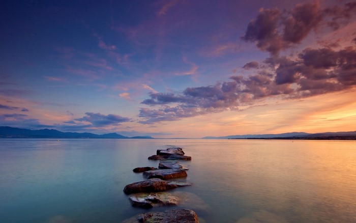 Stepping stones path across a calm sea at sunset