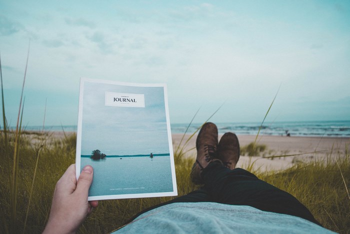 Person reading a journal on the beach