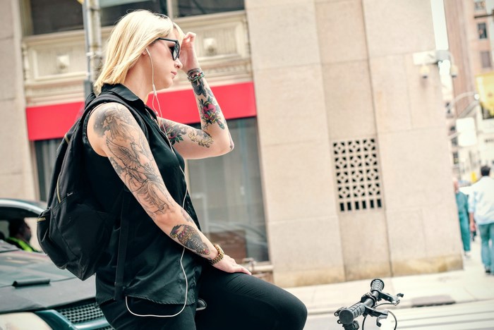 Woman with tattoos and headphones on a bike
