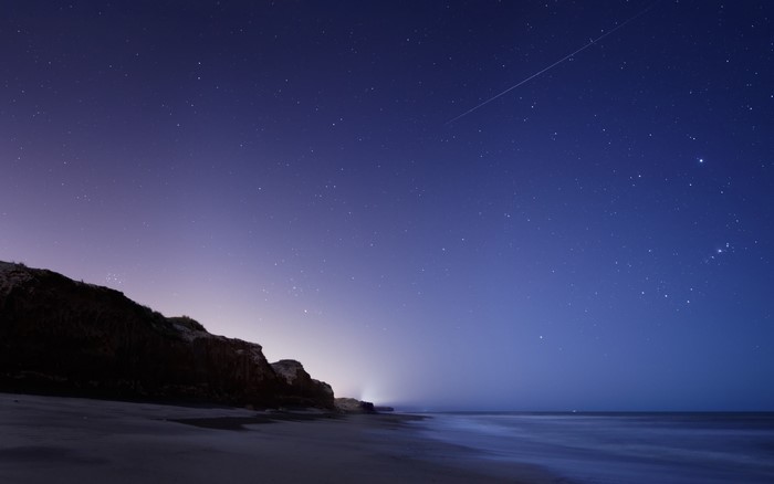 Night sky over a beach with a shooting star