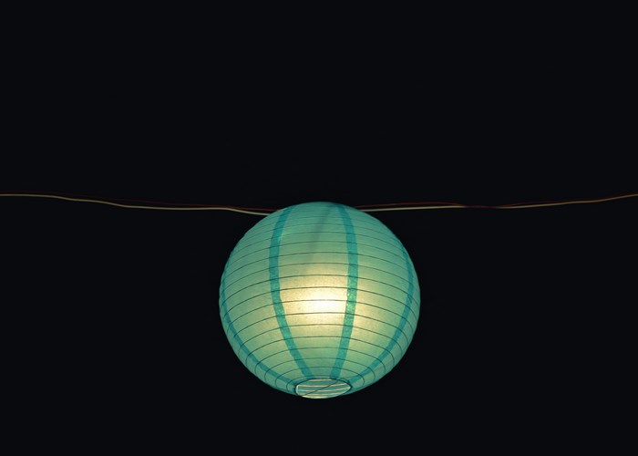 Turquoise paper lantern glowing in the dark