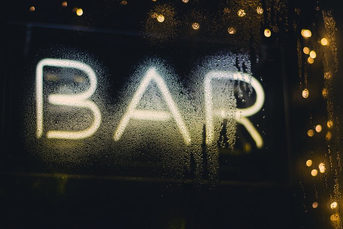 Neon BAR sign on a wet window at night