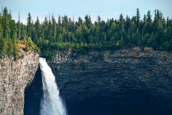 Waterfall cascading over a rocky cliff with a forest