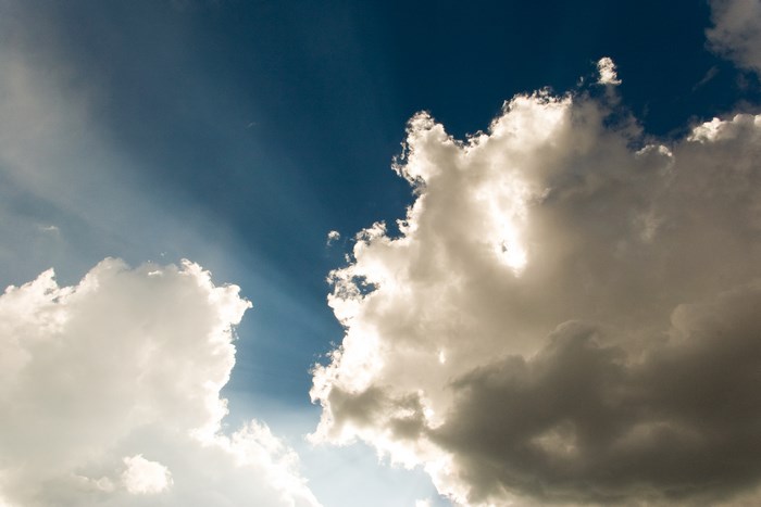 Sunbeams piercing through dramatic clouds in a blue sky