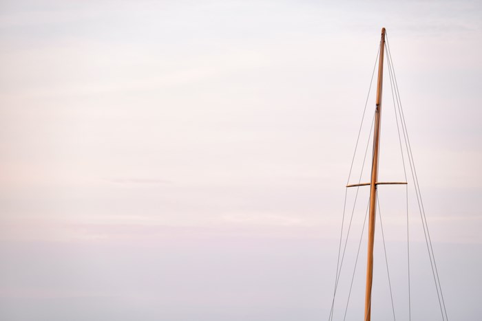 Wooden mast with rigging against a pale sky