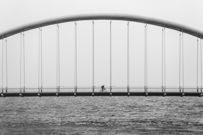 Cyclist on a Suspension Bridge Over Water
