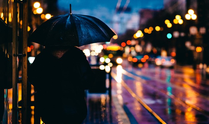 Person with umbrella on a rainy city street at night