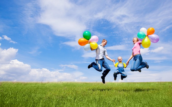 Family jumping with balloons in a field
