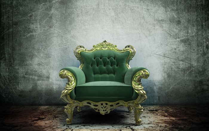 Ornate green armchair against a textured wall