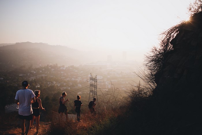 Group hiking on a hill overlooking a city at sunset