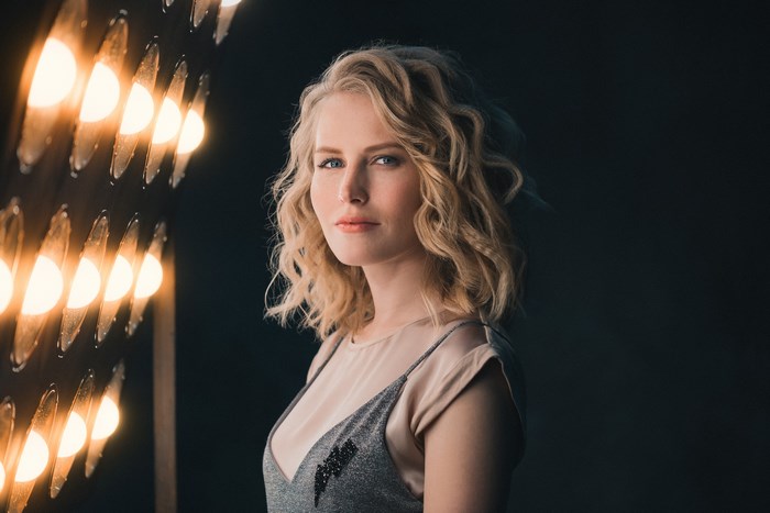 Blonde woman posing in front of stage lights