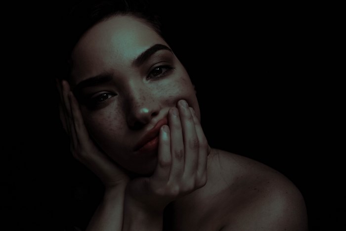 Woman with freckles holding her face