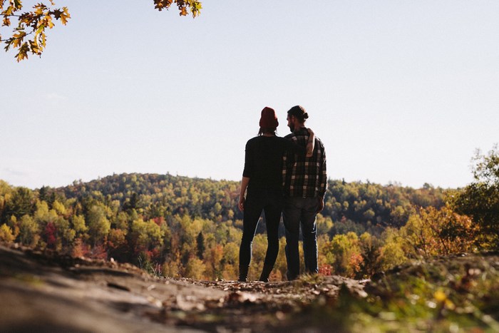 Couple embracing and looking at autumn forest landscape