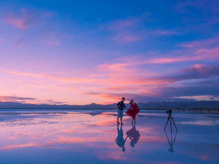 Couple posing on a reflective salt flat at sunset