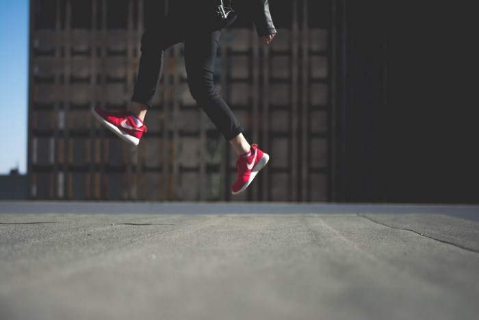 Person in Nike shoes jumping in front of a building