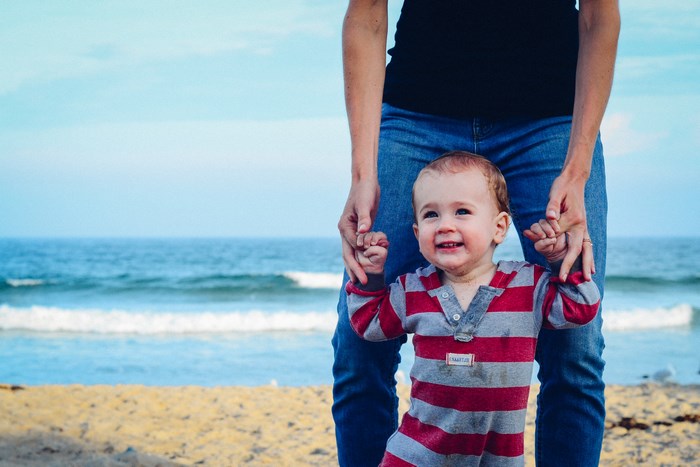 Parent and child holding hands on a beach